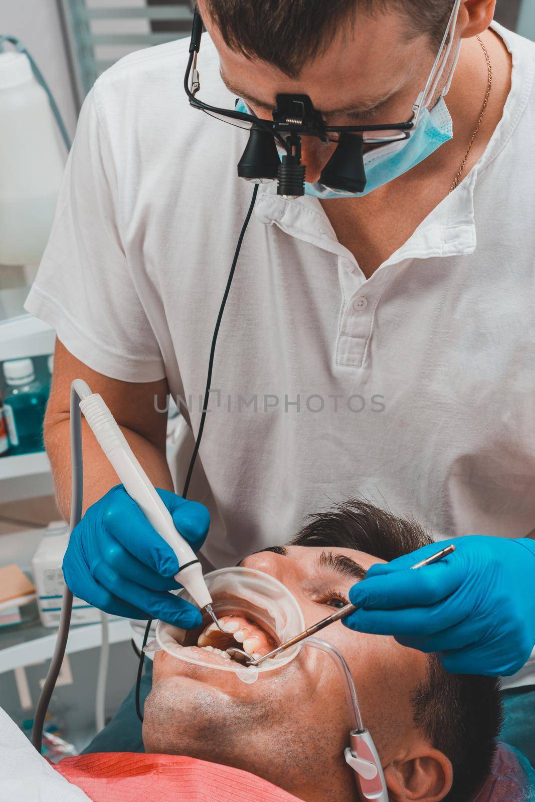 Dentist in the clinic,tartar removal procedure,the dentist in binoculars removes tartar in the patient's mouth.2020