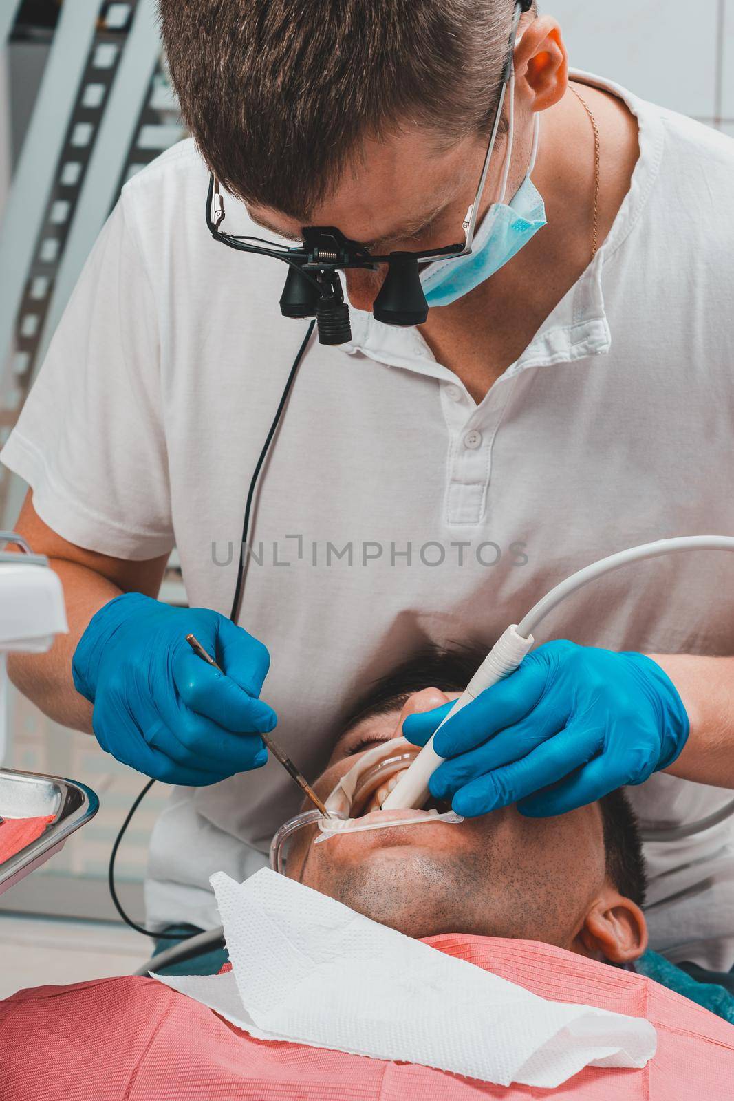 Dentist in the clinic,tartar removal procedure,the dentist in binoculars removes tartar in the patient's mouth.2020