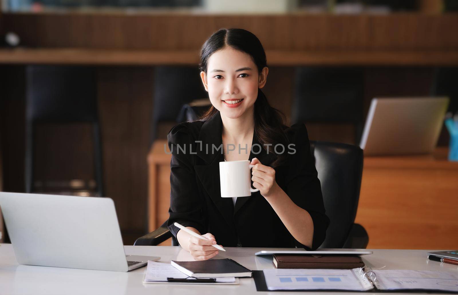 Company employees are sitting at work using computers, tablets and documents in their work. by Manastrong