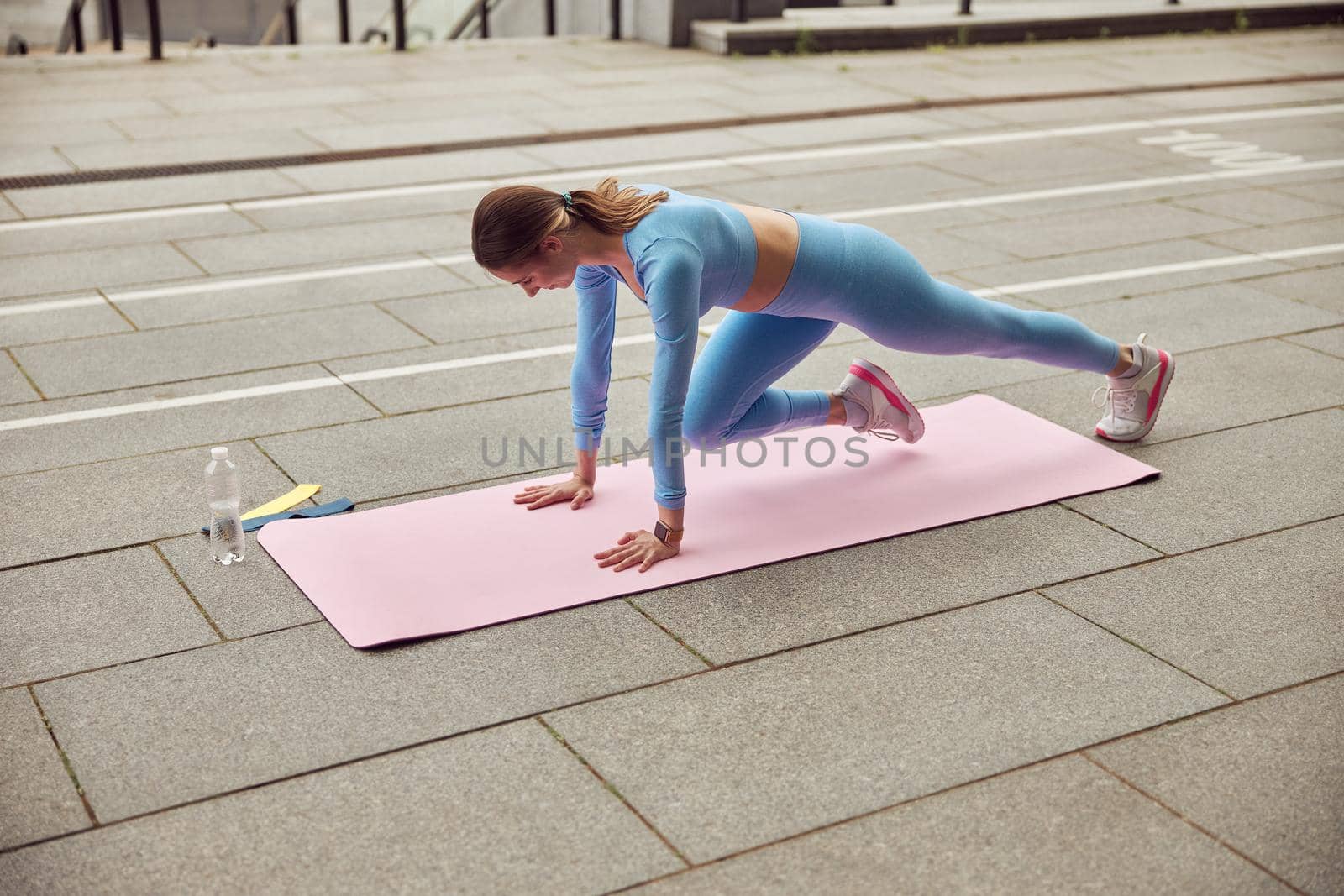 Beautiful fit caucasian woman is doing exercises outdoors at the city by Yaroslav_astakhov