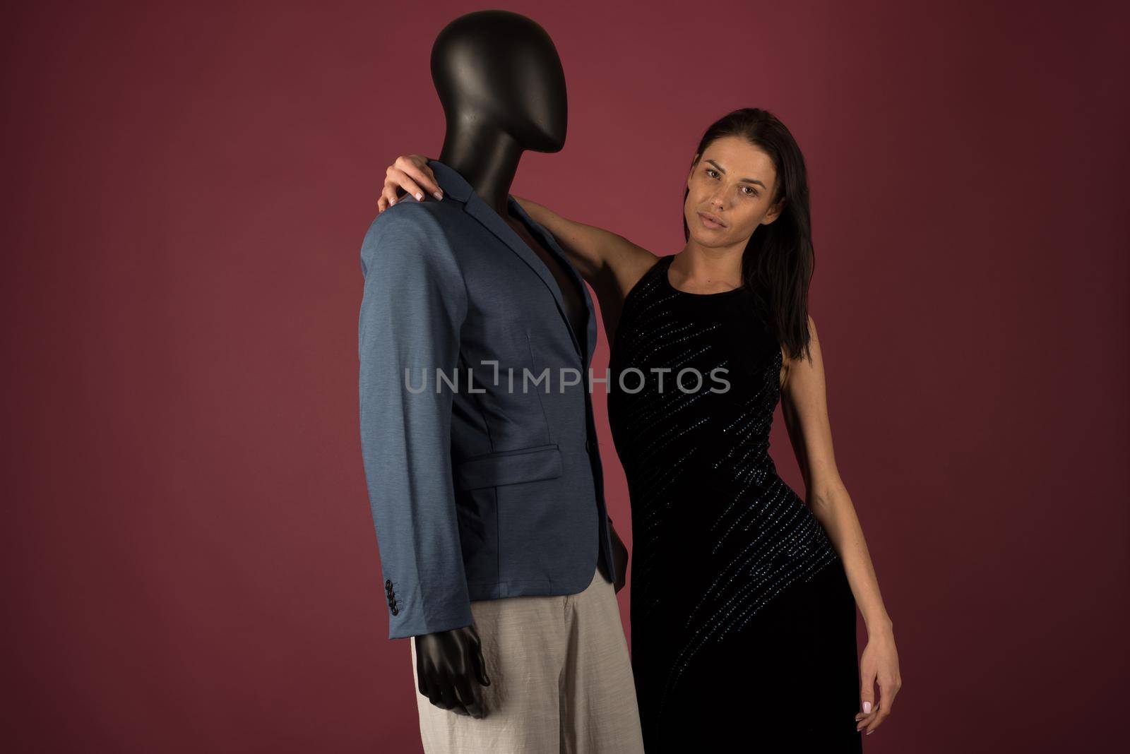A young girl with problematic skin suffers from loneliness in a society of stylish manikins on ruby background.