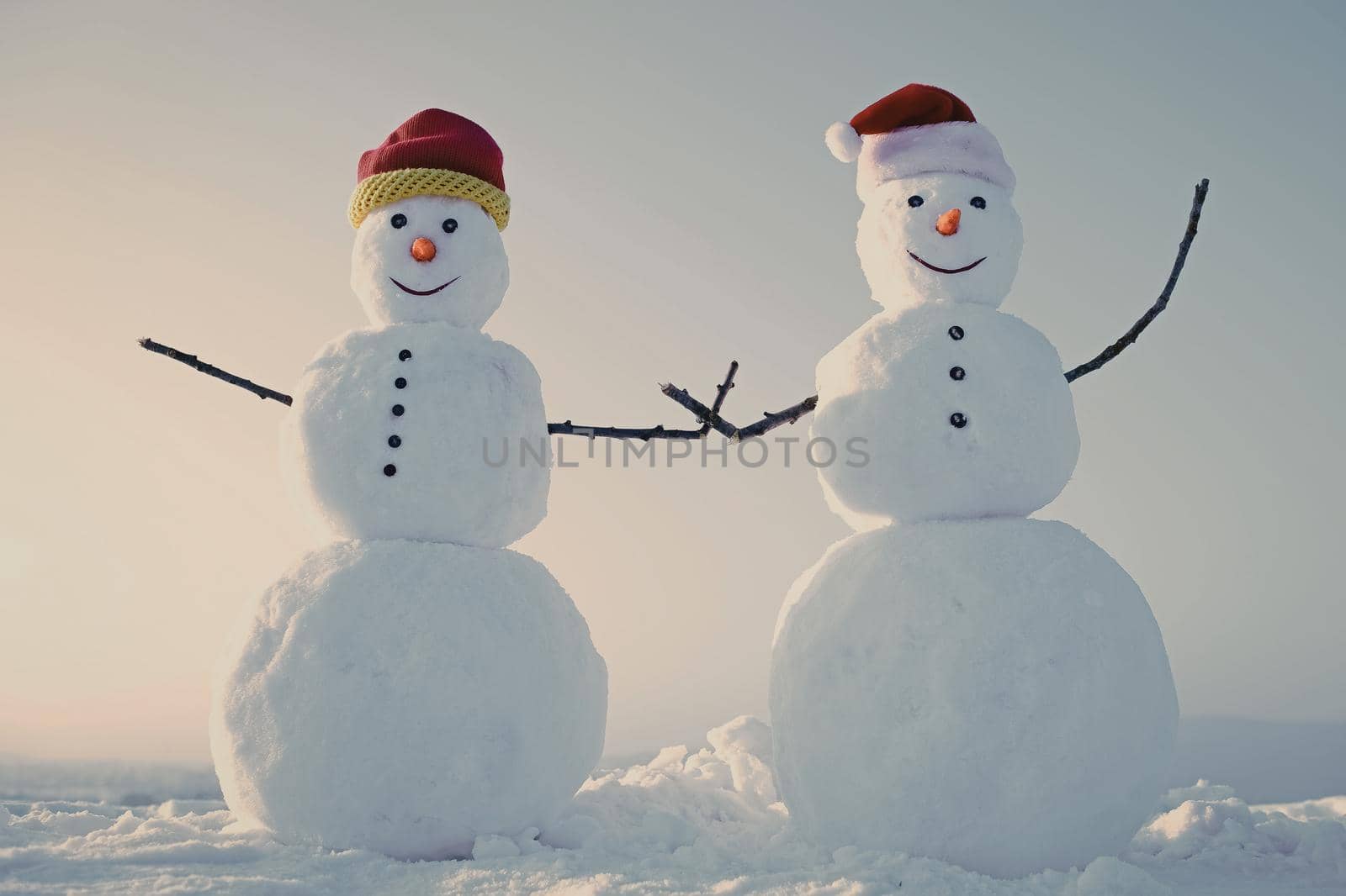 Couple Snowman in winter outdoor. New year snowmen from snow in santa hat.