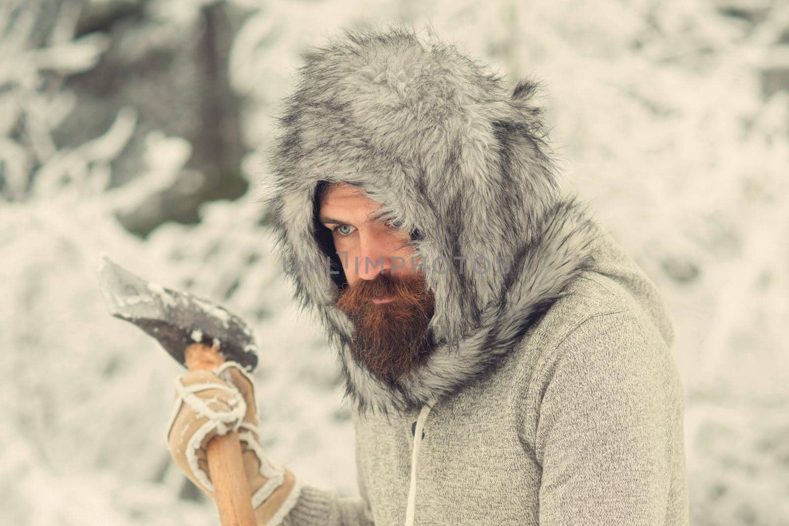 Man lumberjack with axe. Bearded man with axe in snowy forest. Angry face closeup