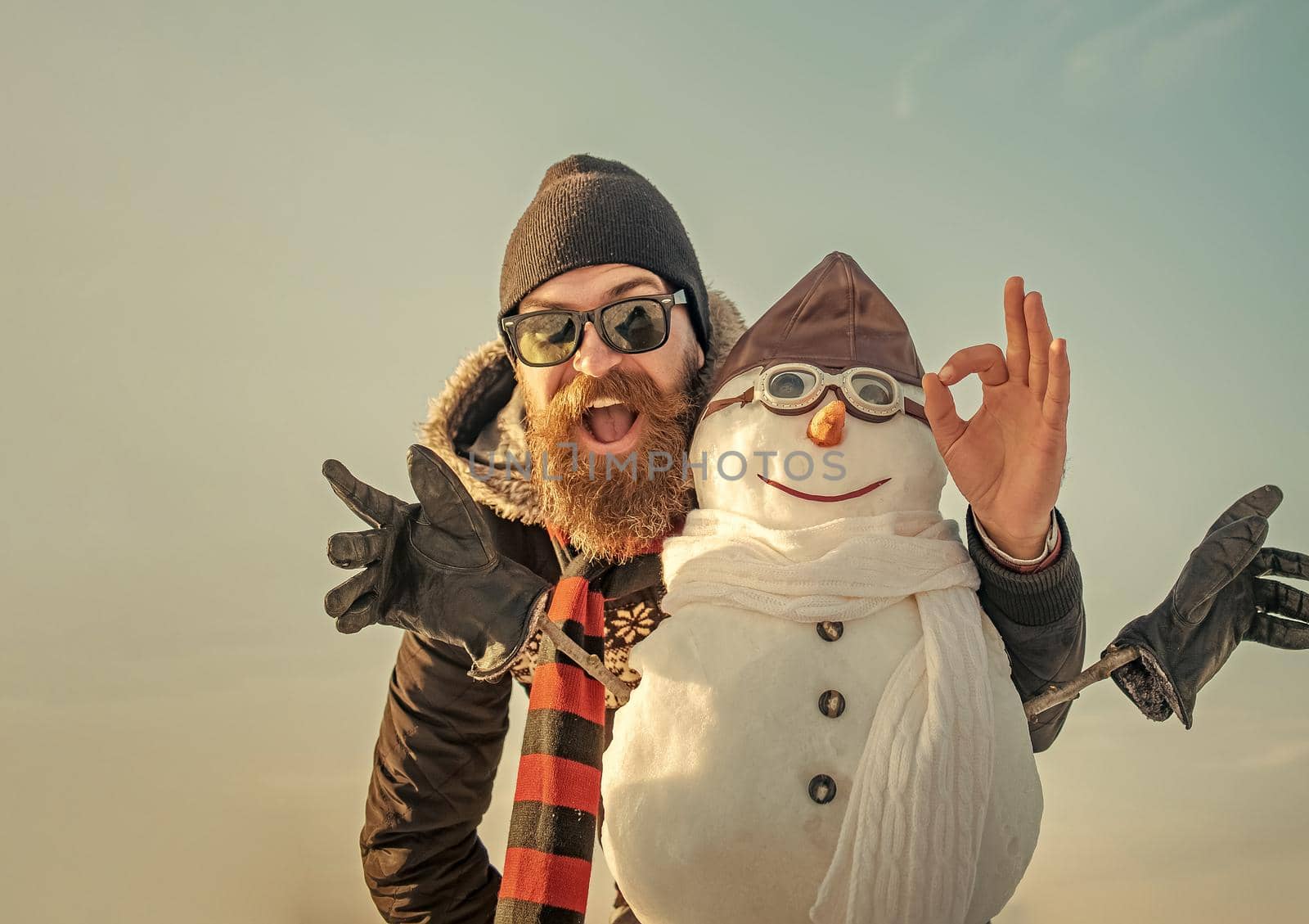 Winter man with snowman in pilot hat. Christmas man with beard on happy face. Snowman pilot, winter holiday celebration