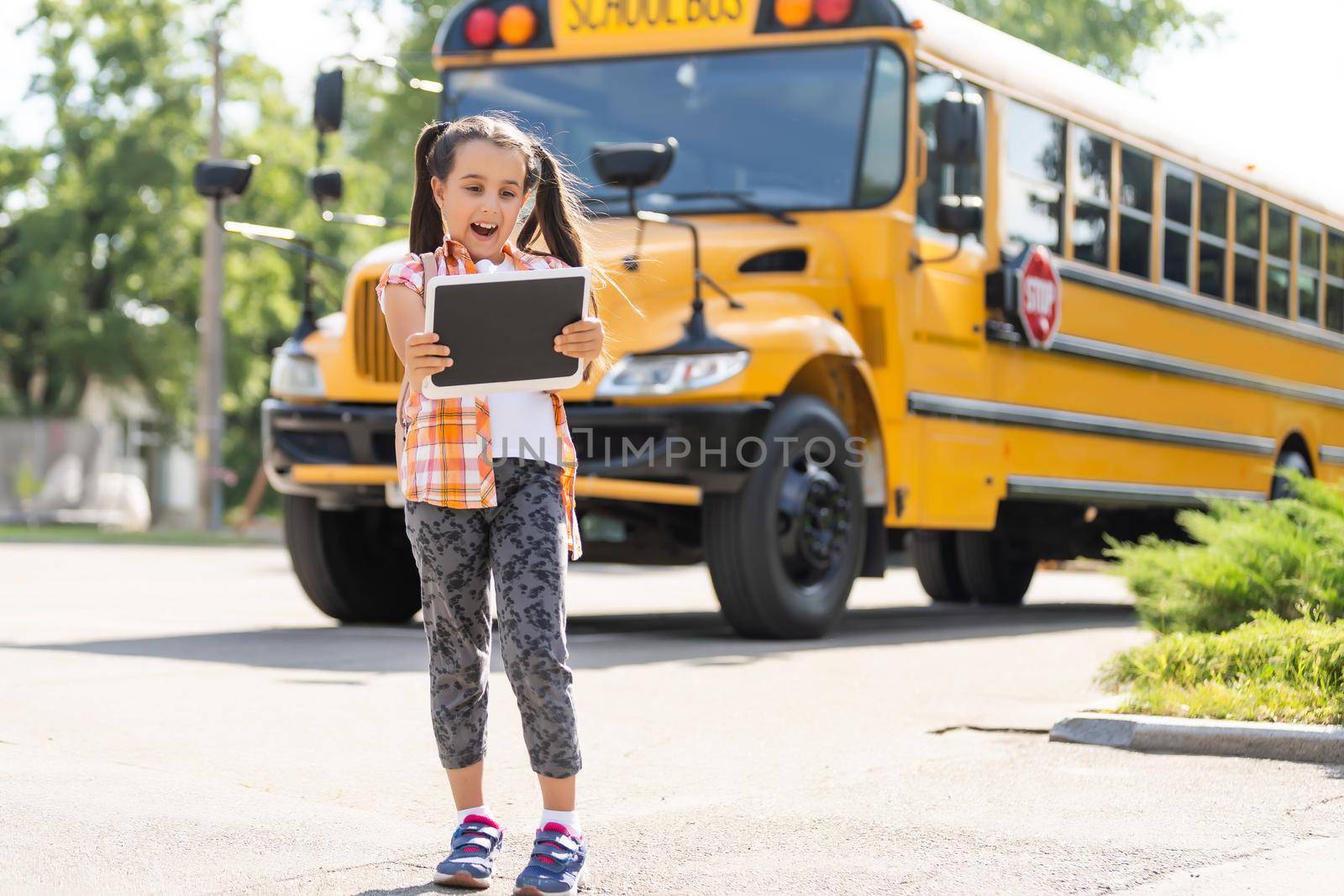 Little girl standing by a big school bus door with her backpack.