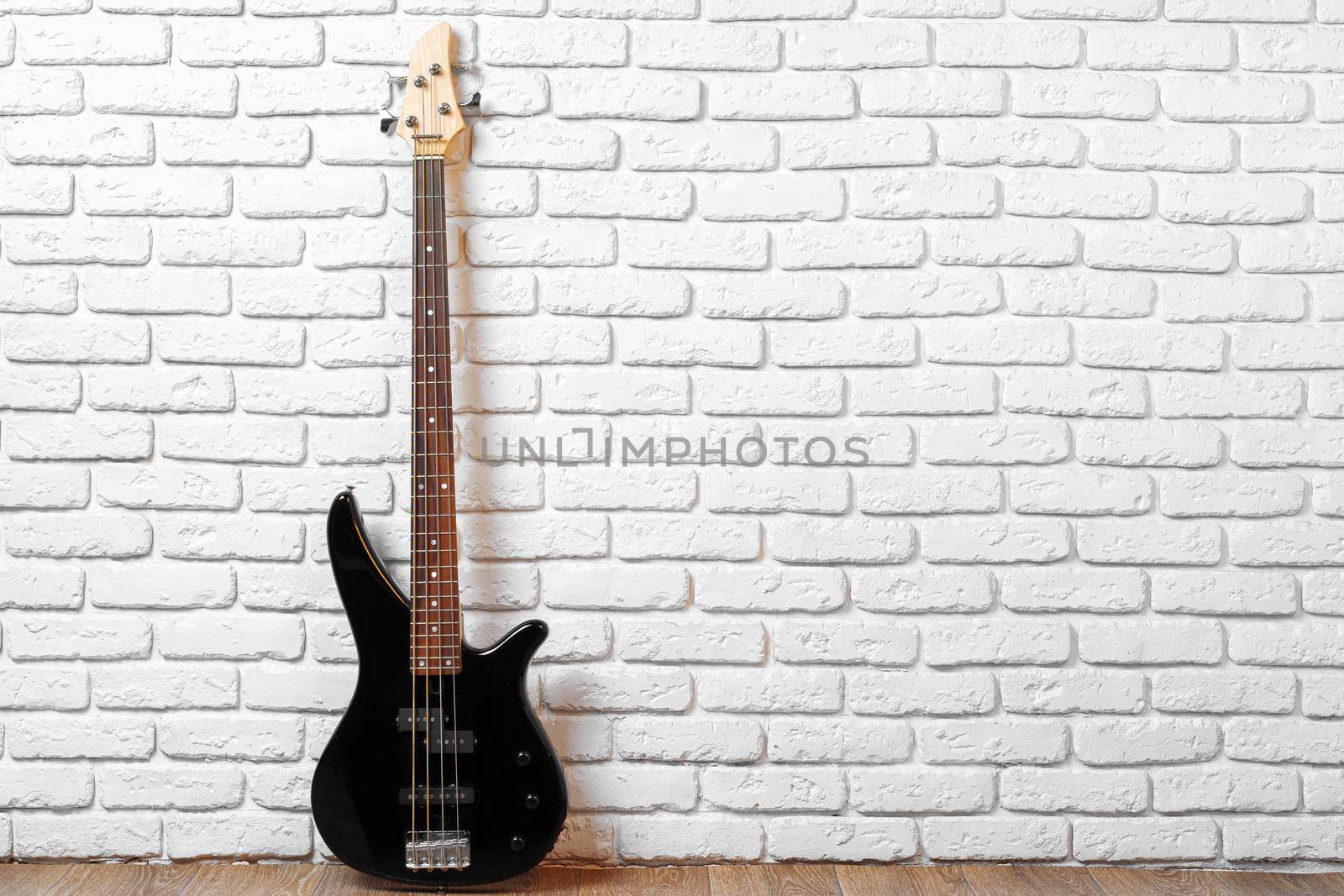One guitar on the floor against white brick wall, copy space