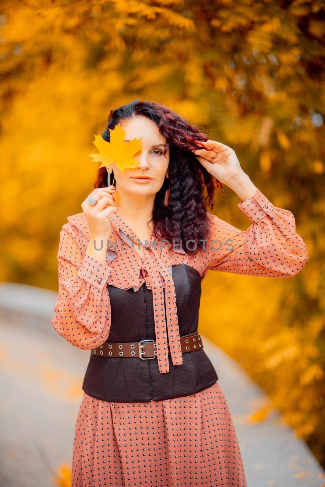 Beautiful girl walking outdoors in autumn. Smiling girl collects yellow leaves in autumn. Young woman enjoying autumn weather. by Matiunina