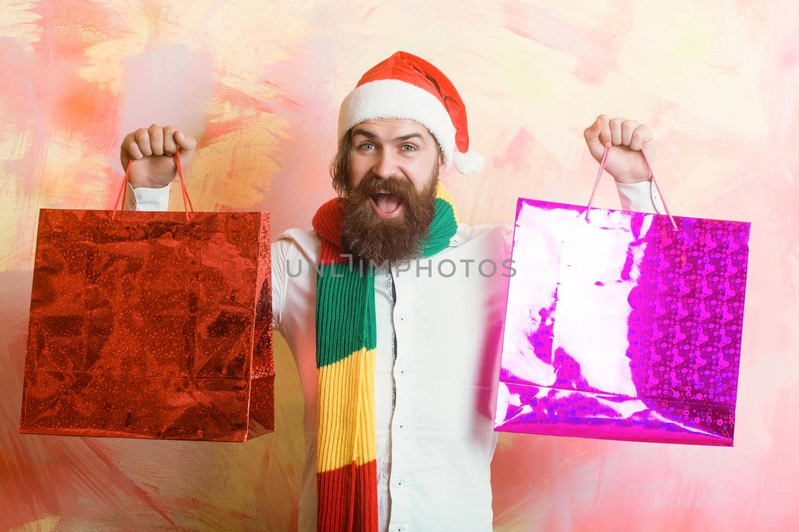 Happy man with beard in red santa hat with shopping bag