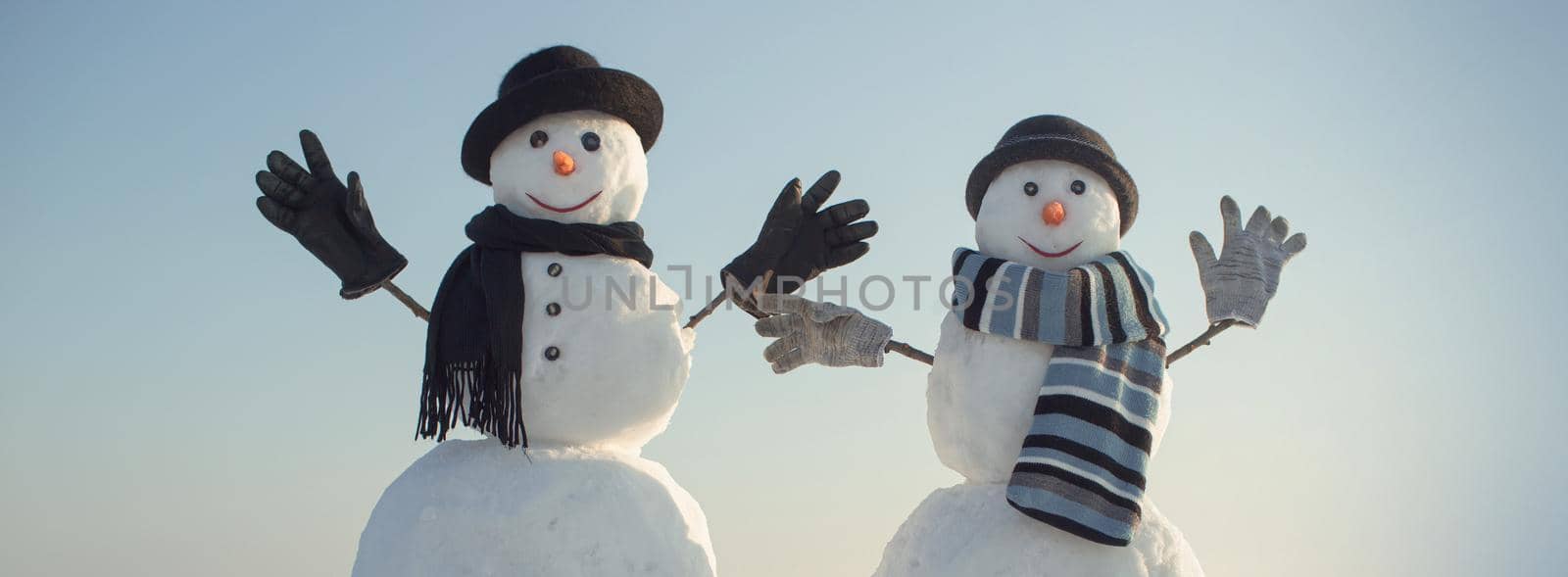 Couple snowman with hat and scarf in winter outdoor. New year snowmen from snow in santa hat. by Tverdokhlib