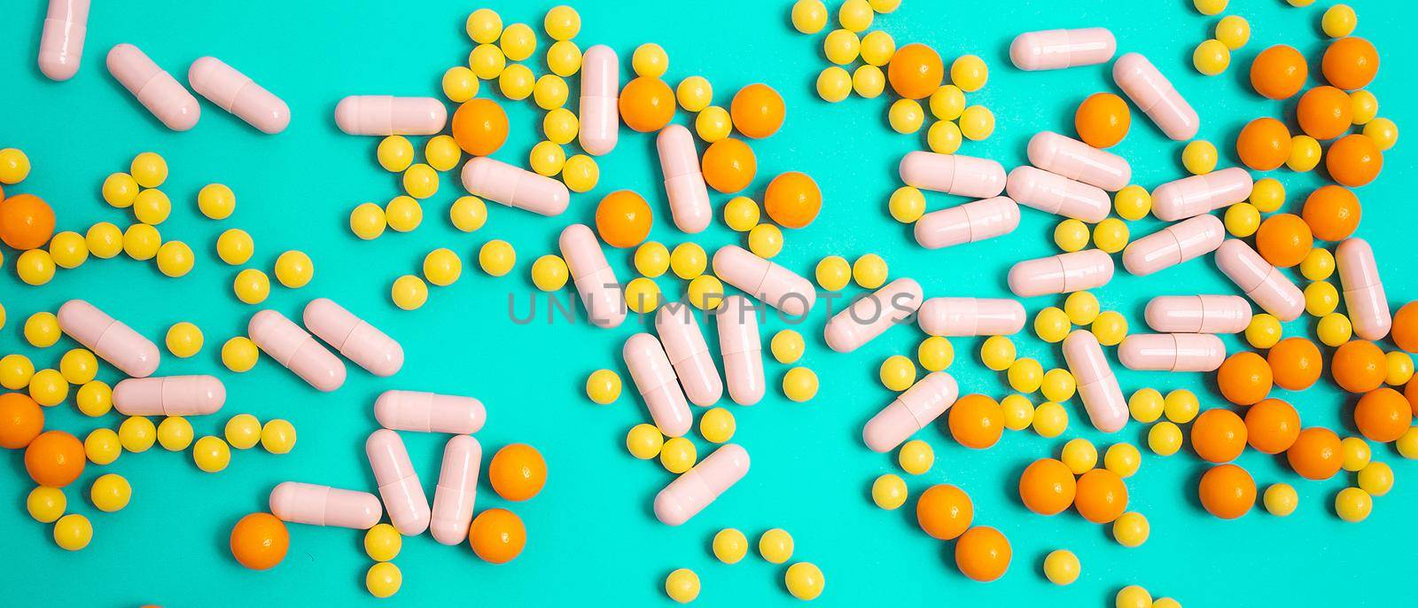 different colorful and white pills, capsules. Prevention, cure of influenza, coronavirus, covid-19. yellow, orange vitamins, tablets on blue background. medical healthcare, protection concept banner