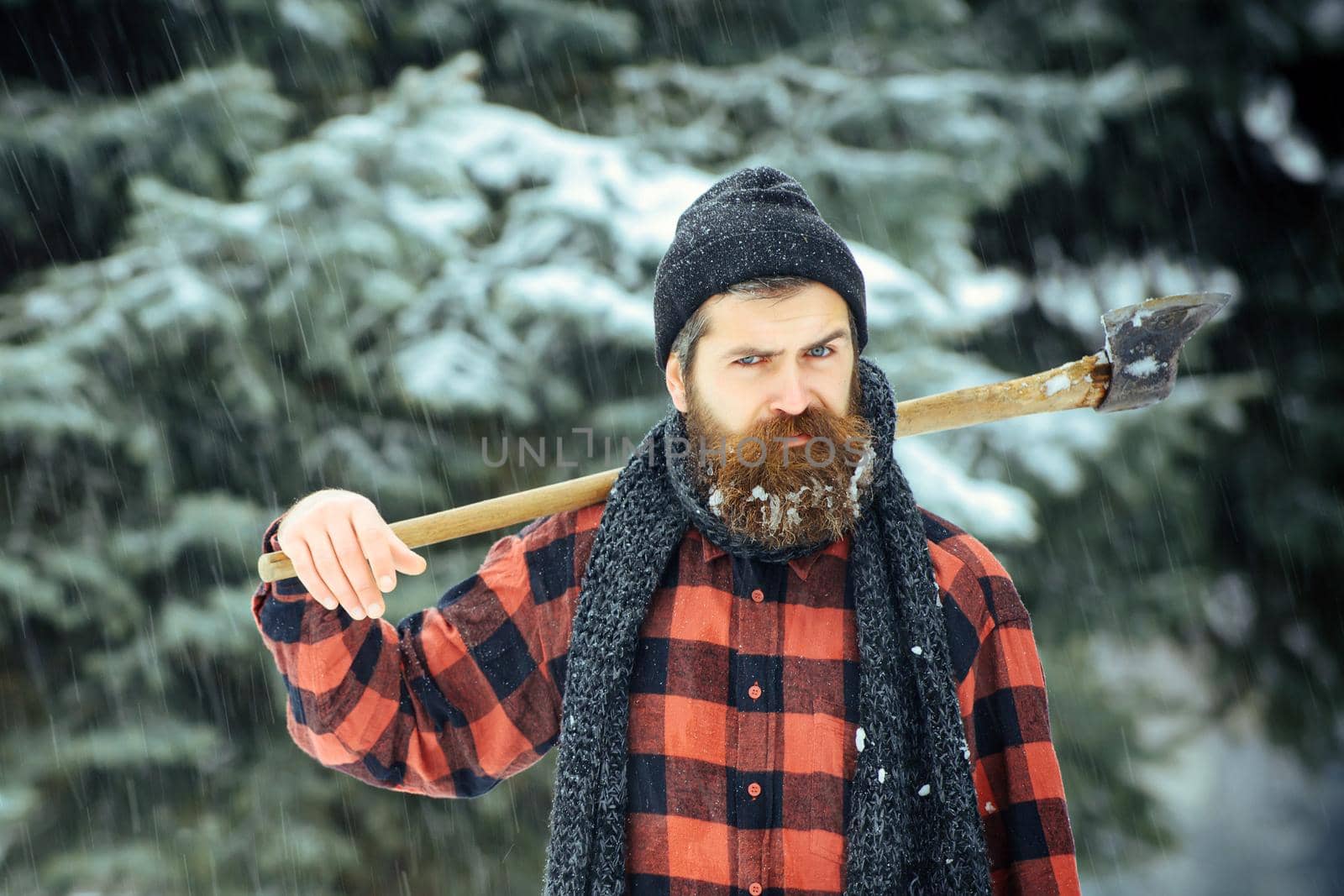 Serious man lumberjack with axe outdoor in winter by Tverdokhlib