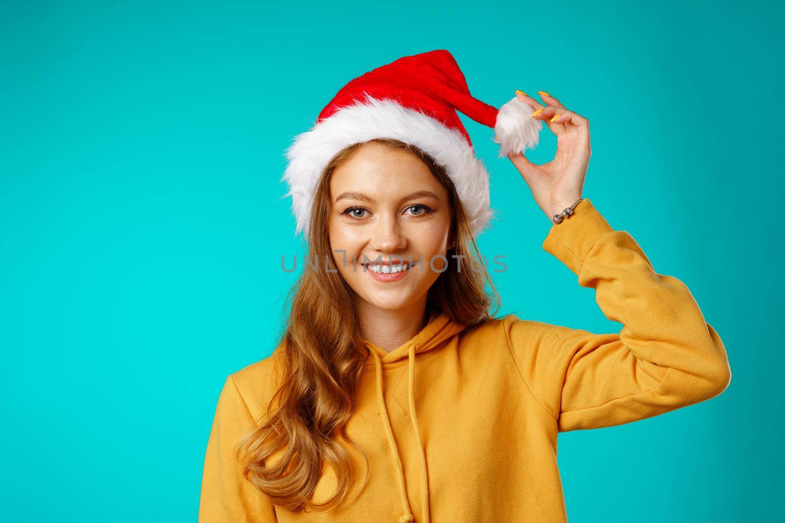 Young smiling woman wearing santa claus hat against blue background