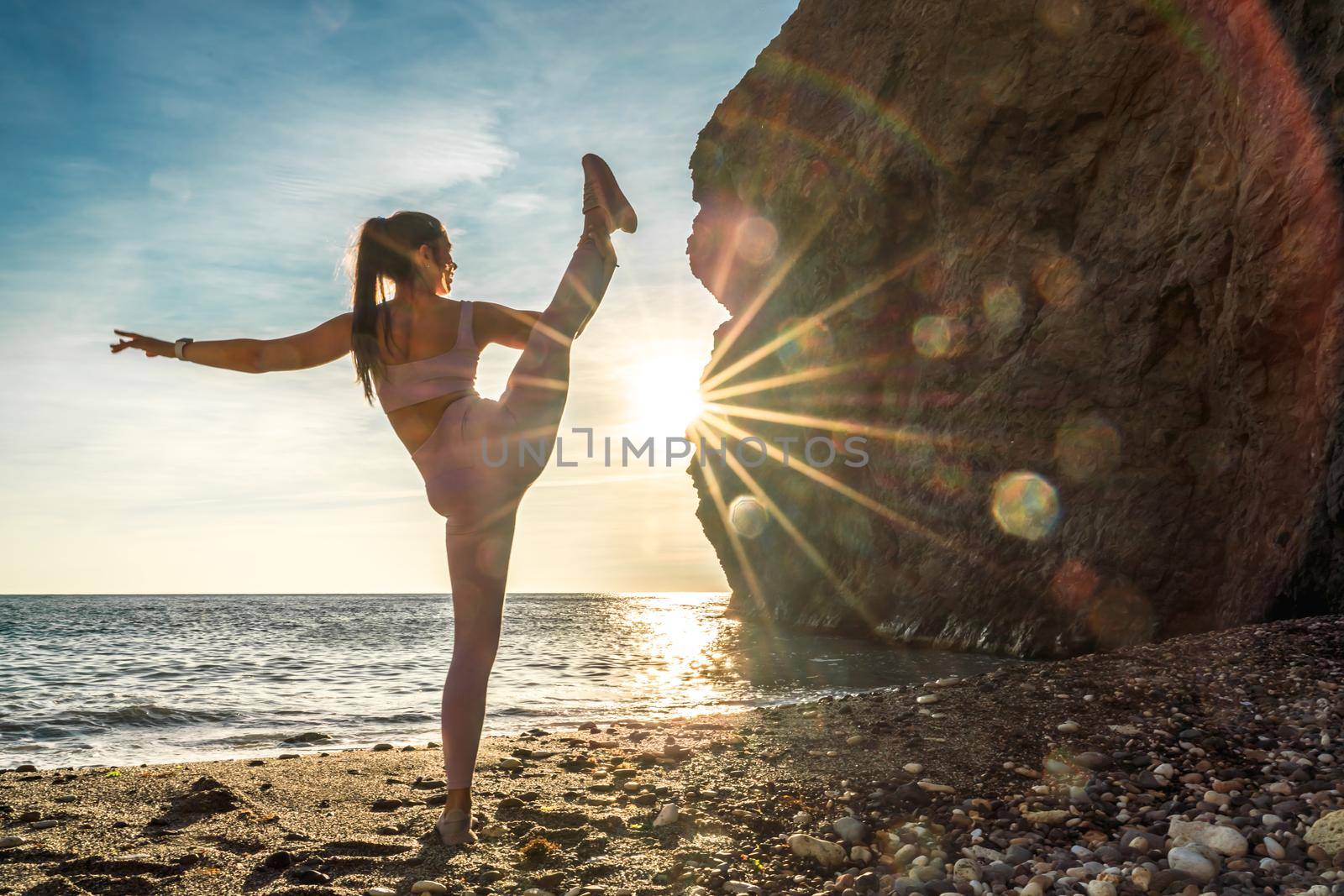 Girl gymnast is training on the beach by the sea sunset. Does twine. Photo series