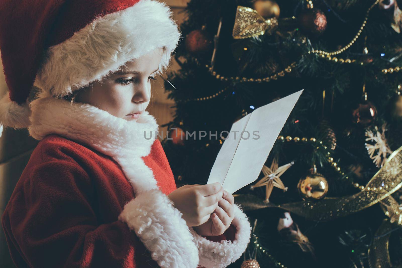 New year small girl with wish letter to Santa. Christmas happy child read wish letter