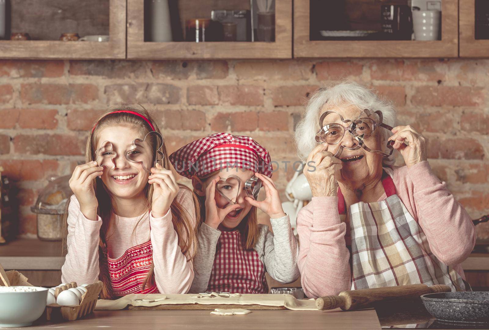 Granny with granddaughters looking at camera through cookie cutters by tan4ikk1