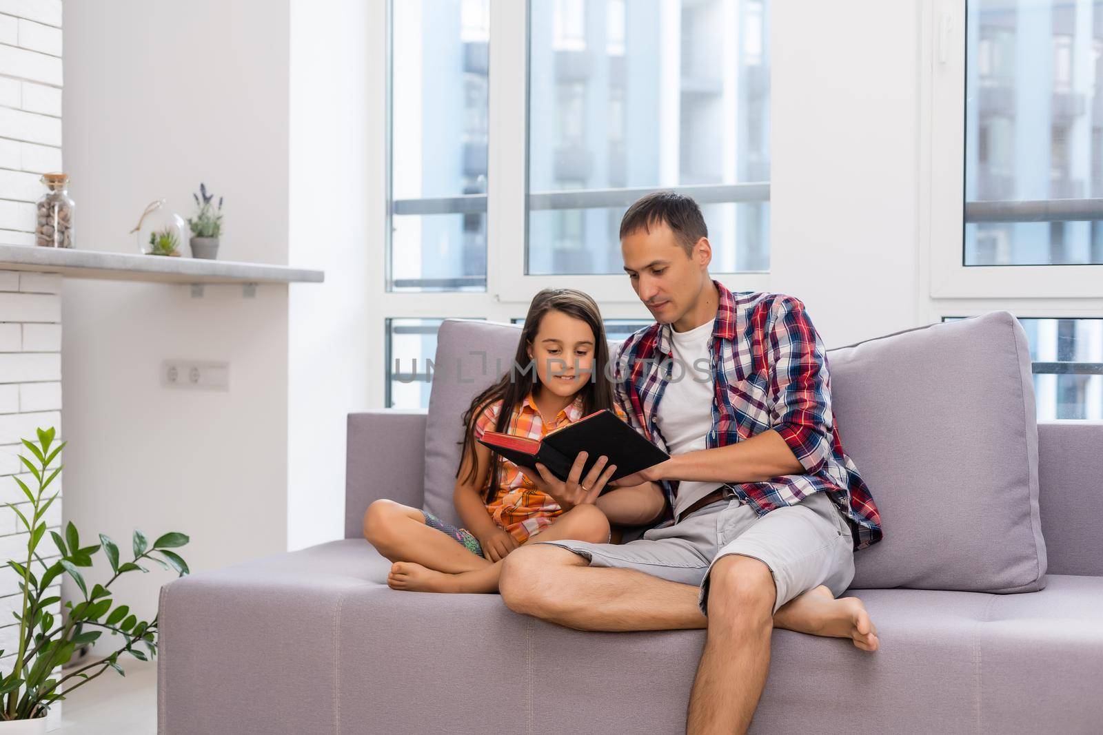 a young father with his little daughter reads the Bible by Andelov13