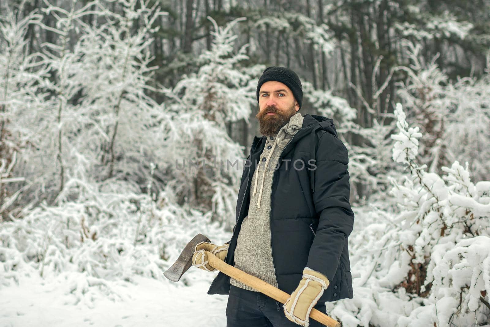 Man lumberjack with axe outdoor in winter. Bearded man with axe in snowy forest