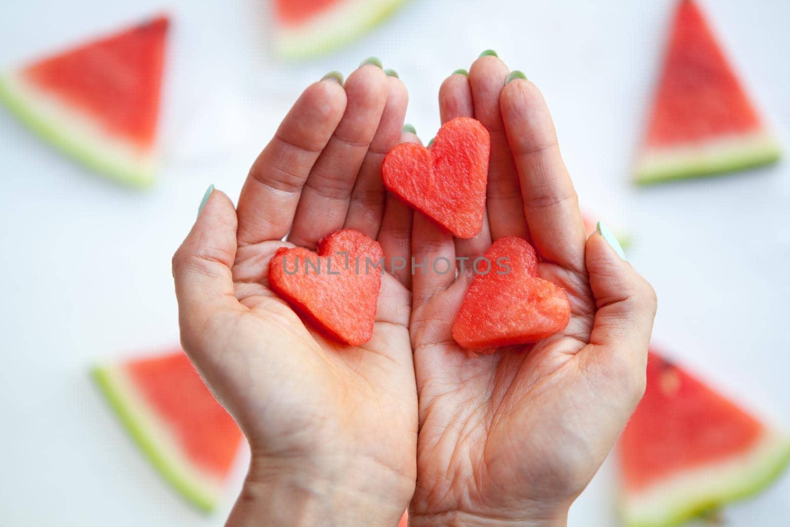 Watermelonhearts slices on womans hands. Sliced watermelon on white background. Flat lay, top view. Love and care concept. by julija