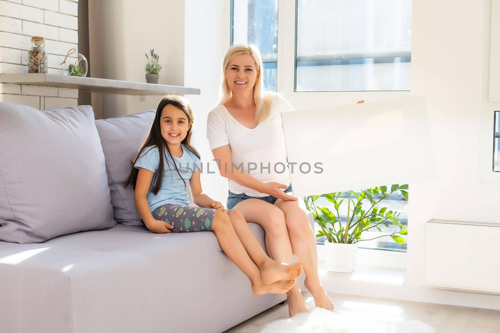 mother and daughter hold photo canvas at home