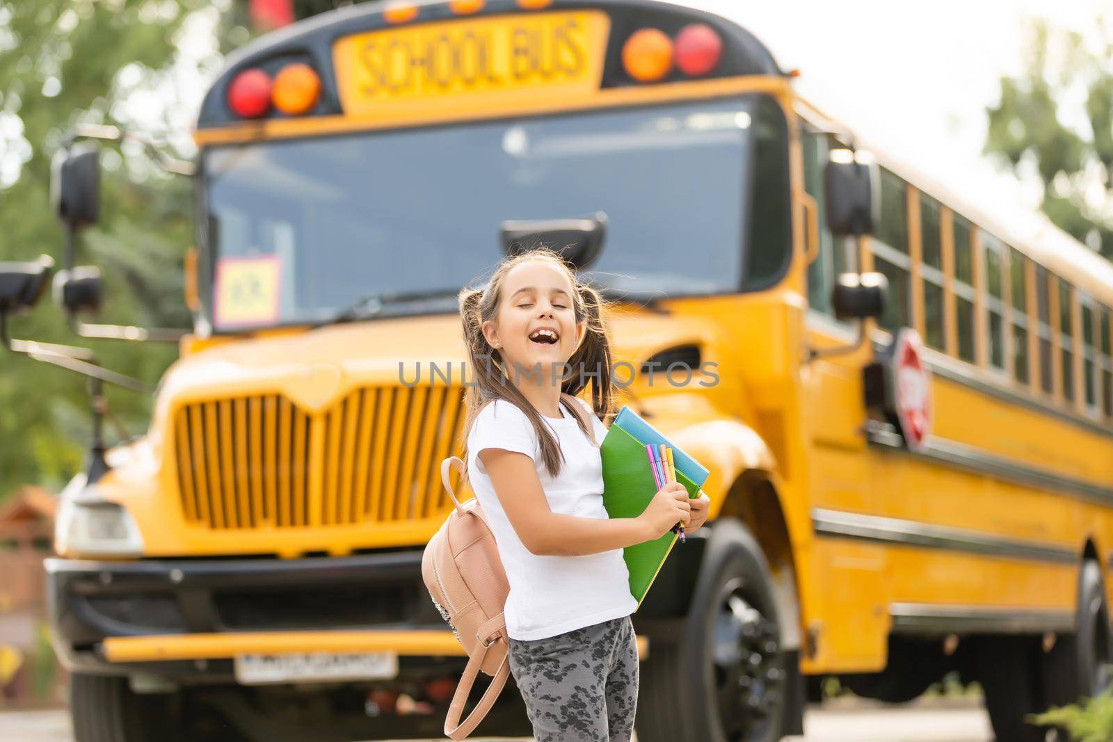 Girl with backpack near yellow school bus. Transport for students