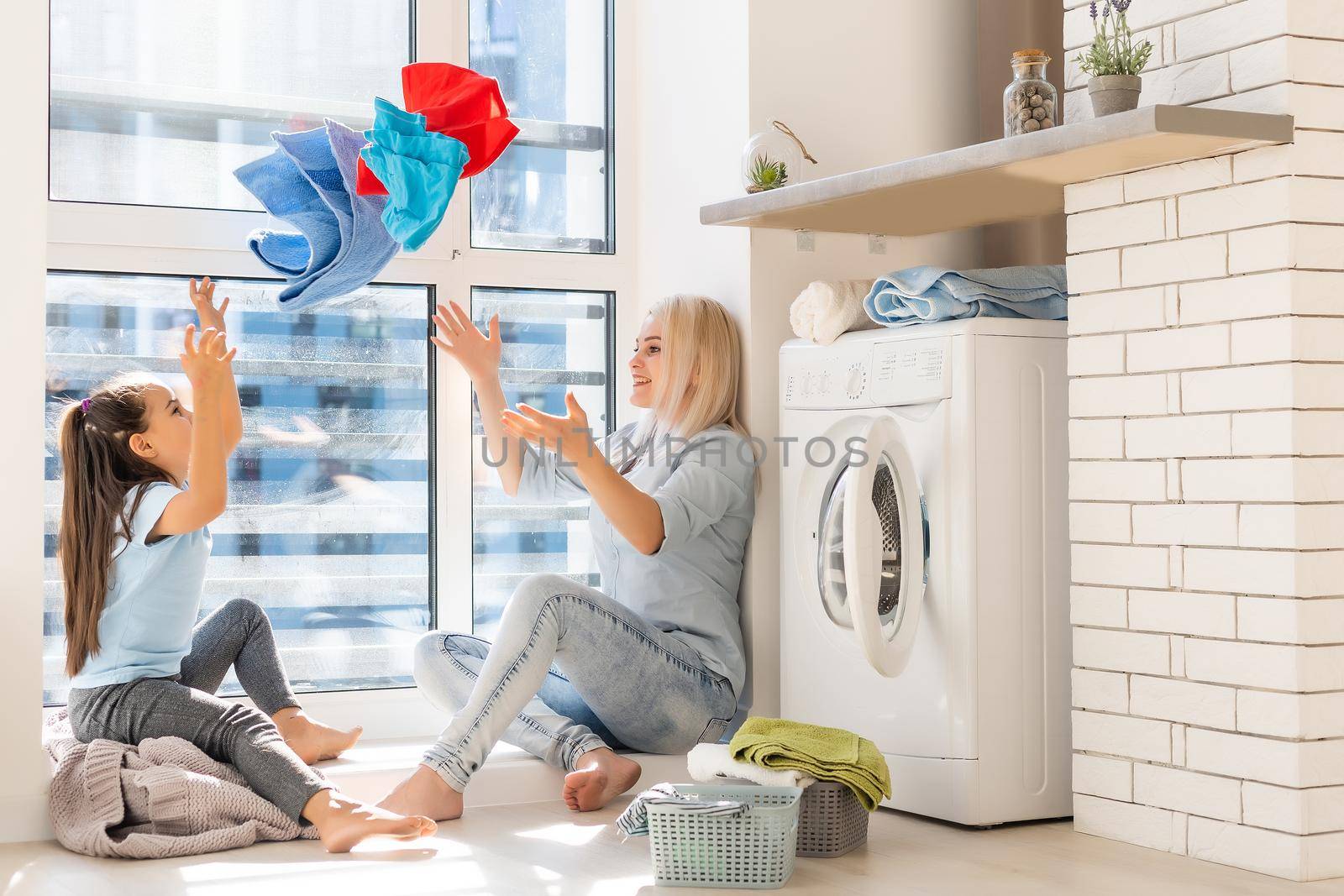 family mother and child girl little helper in laundry room near washing machine and dirty clothes