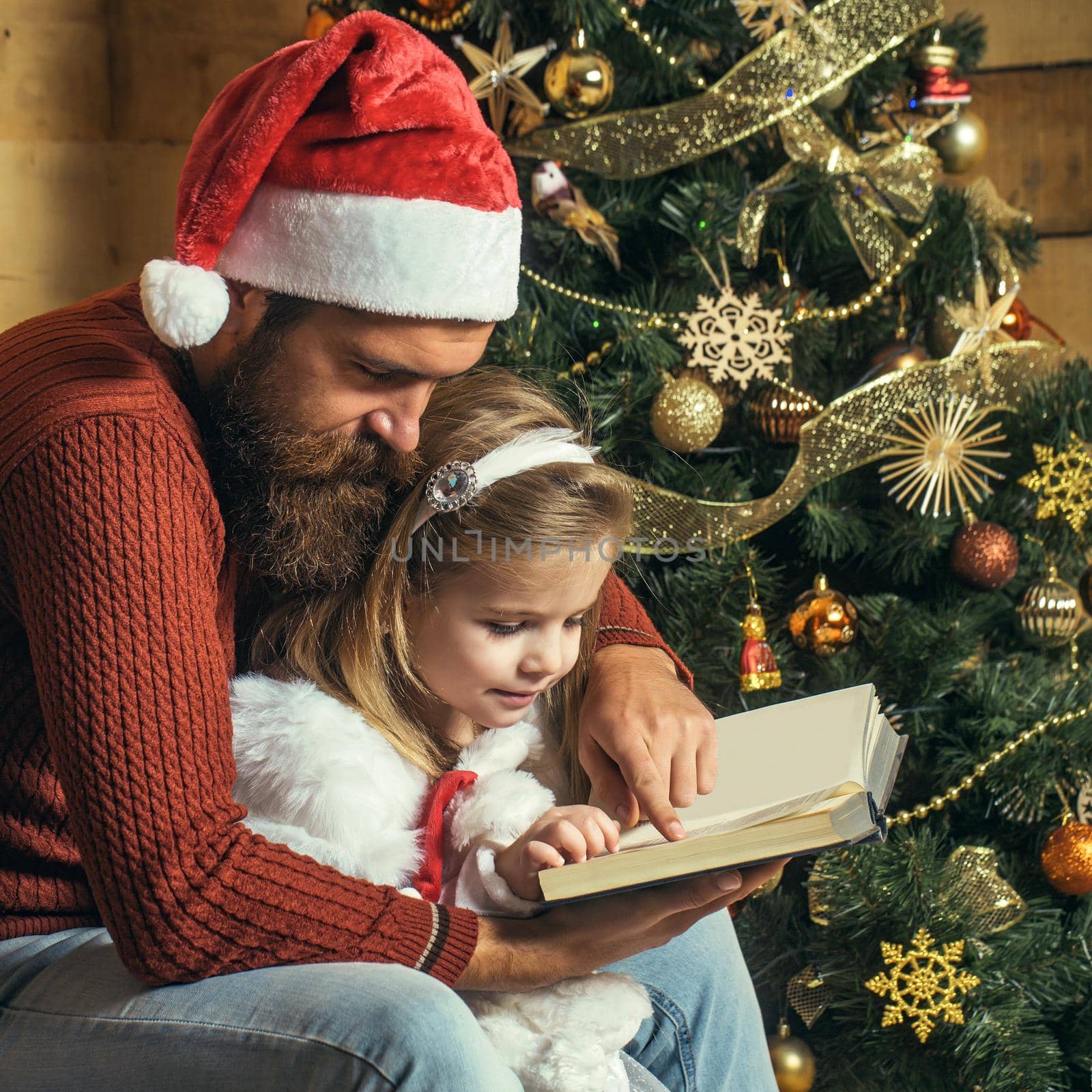Christmas santa father and daughter read book. Winter family holiday at home by Tverdokhlib