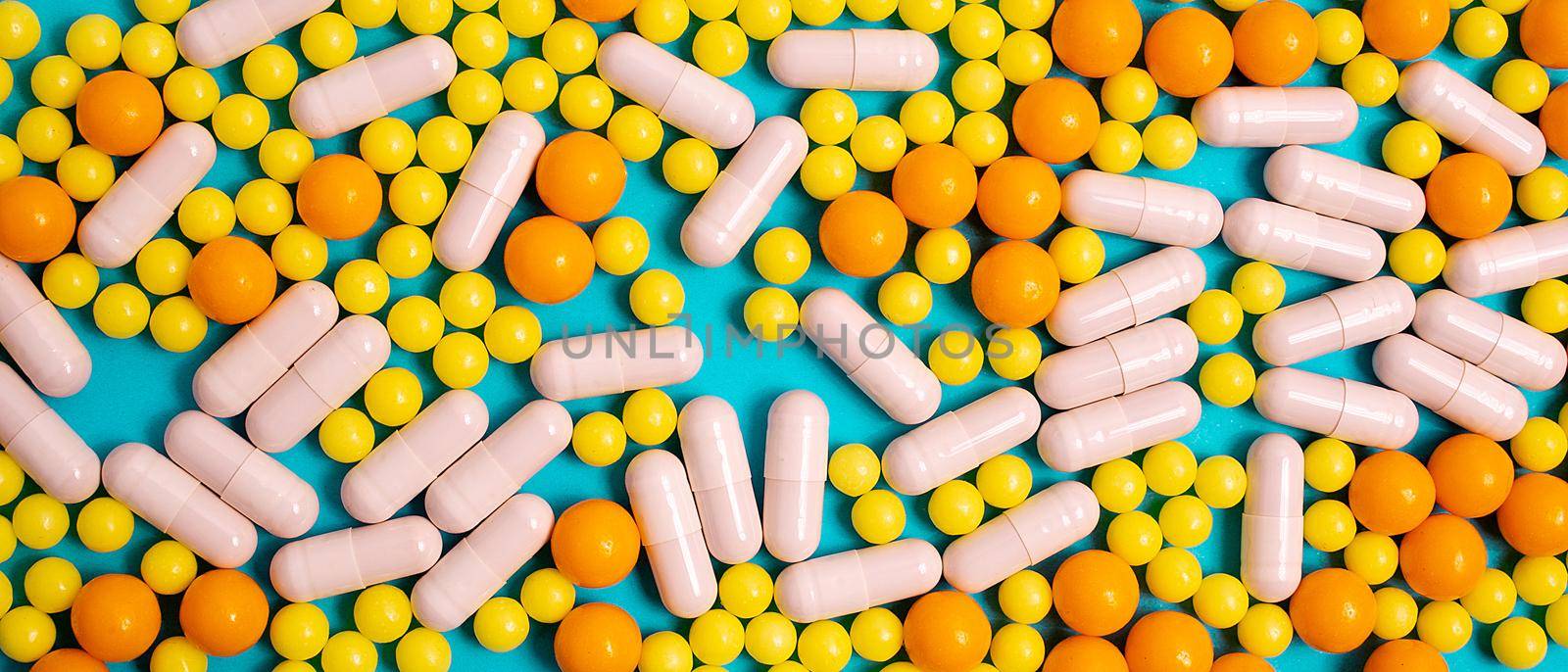 different colorful and white pills, capsules. Prevention, cure of influenza, coronavirus, covid-19. yellow, orange vitamins, tablets on blue background. medical healthcare, protection concept banner