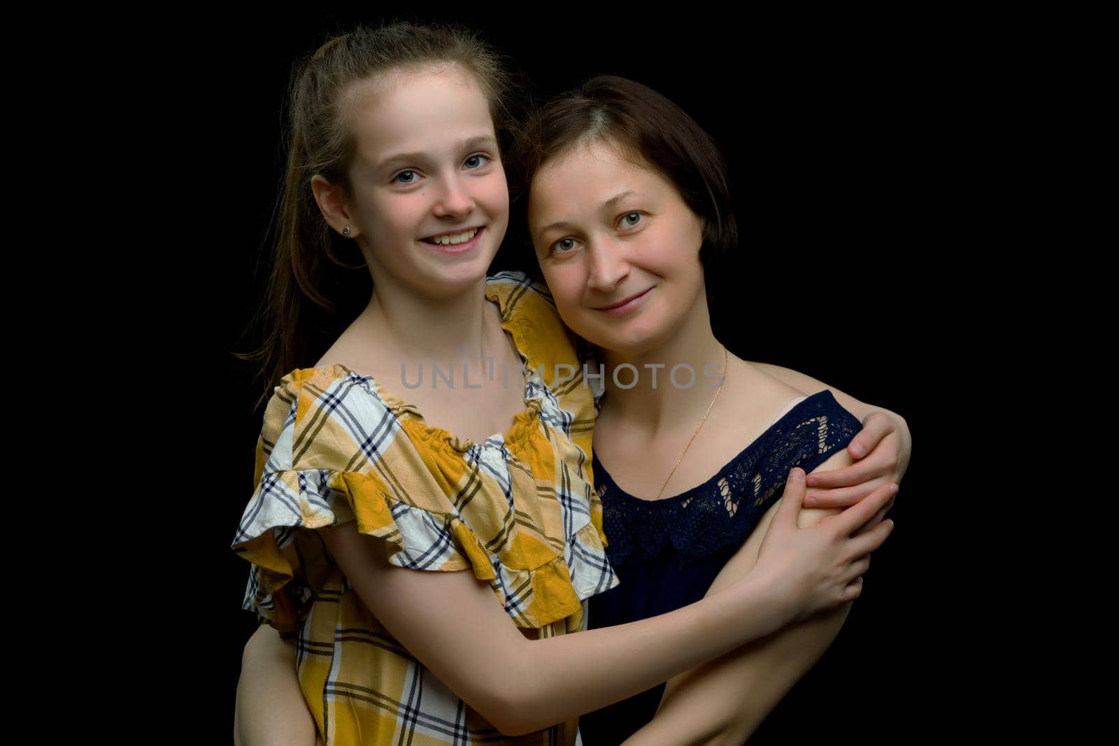 Happy family mom and daughter in the studio on a black background. The concept of love, childhood.