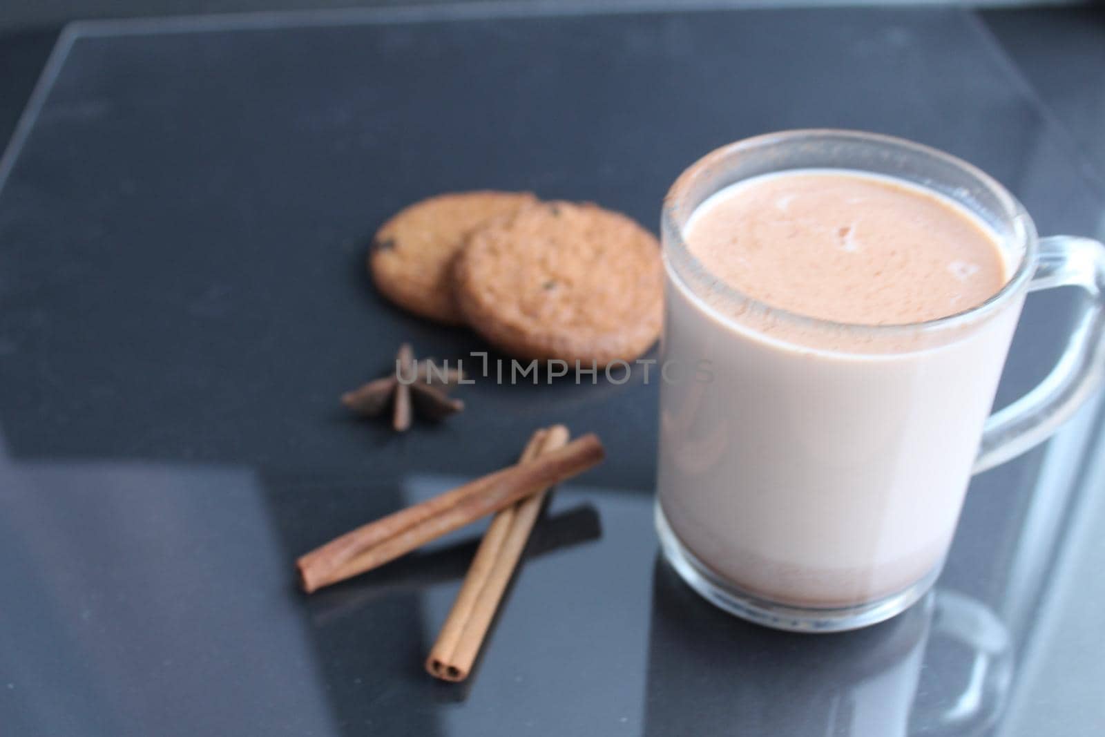 drink hot chocolate cocoa in a glass mug with cinnamon sticks and cookies on a black background with a place for text.