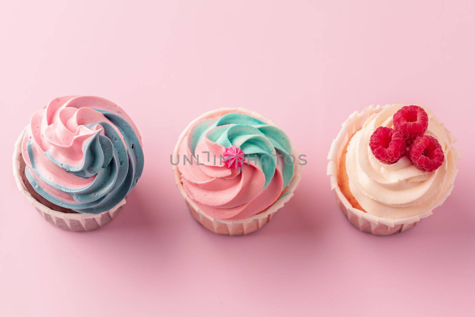 Yummy sweet cupcakes on light pink background