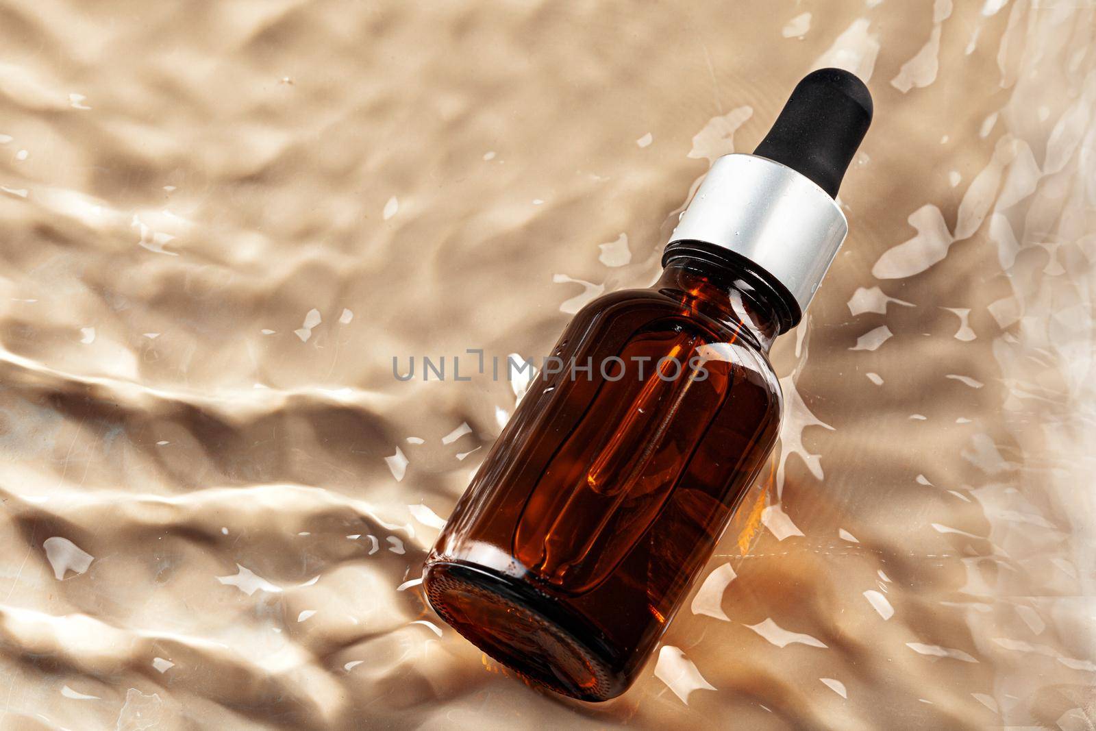 Cosmetic bottle with pipette in wavy water, top view