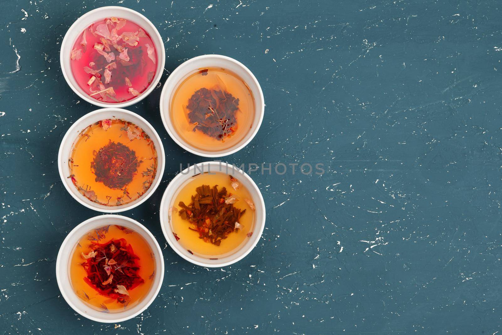 Tea concept. Different kinds of dry tea in ceramic bowls and cups of aromatic tea