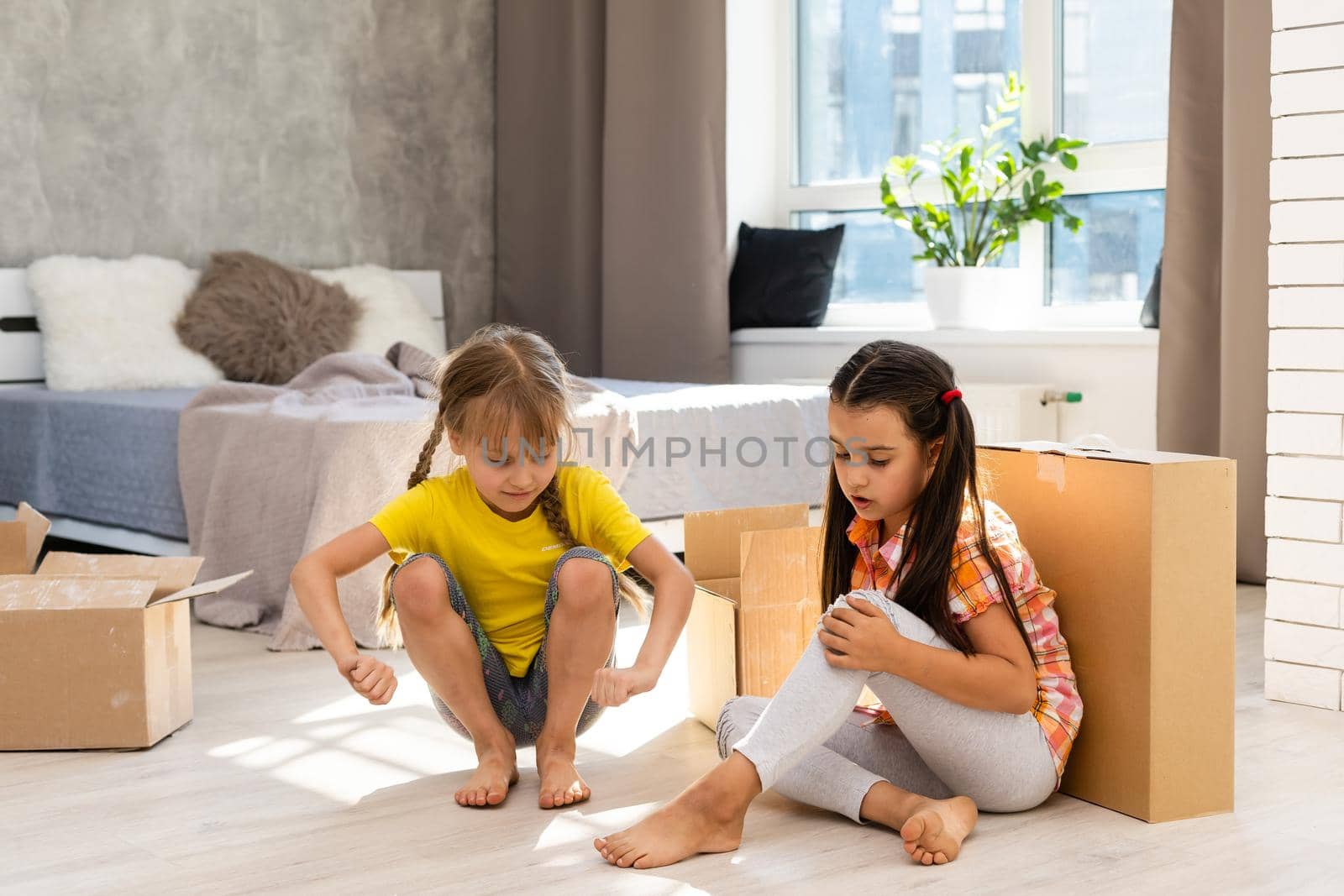 Excited funny kids girls running inside luxury big modern house on moving day, cute children entering exploring new home, happy young family buying real estate