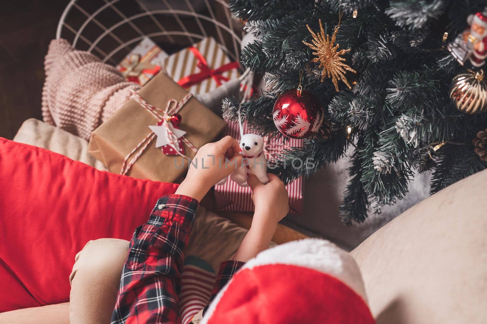 Close-up of child hands hanging decorative toy on Christmas tree branch