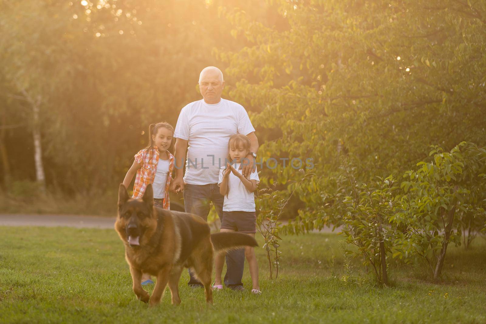 Grandfather And Granddaughters Taking Dog For Walk