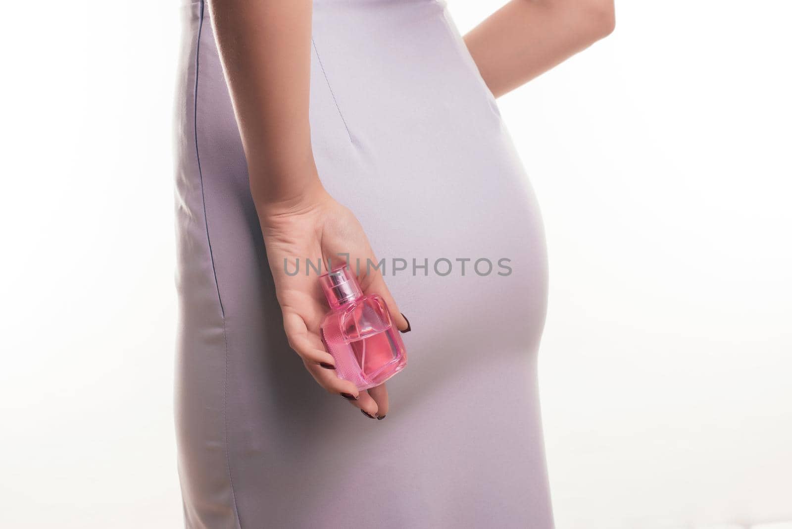 Beautiful young woman with bottle of perfume on white background