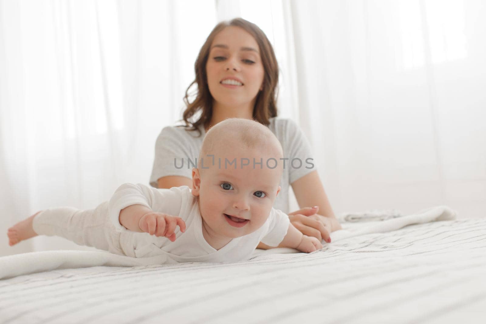 happy family. Mother and baby playing and smiling on the bed