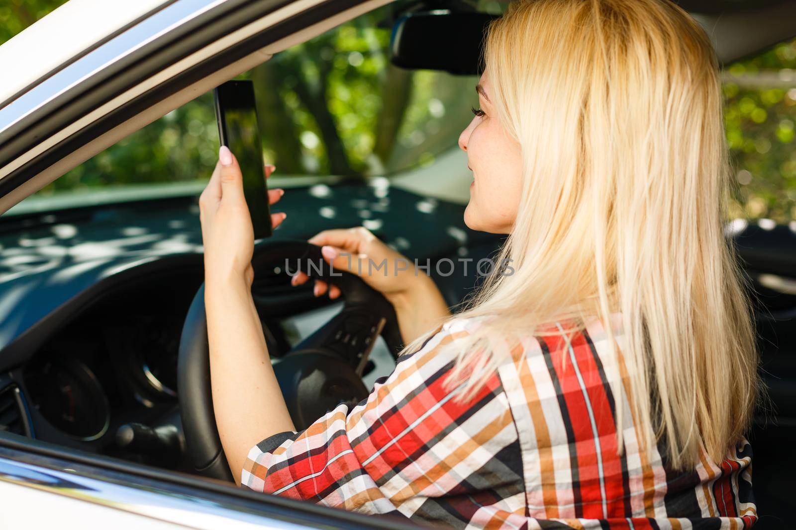 Young woman looking to her smartphone while driving car