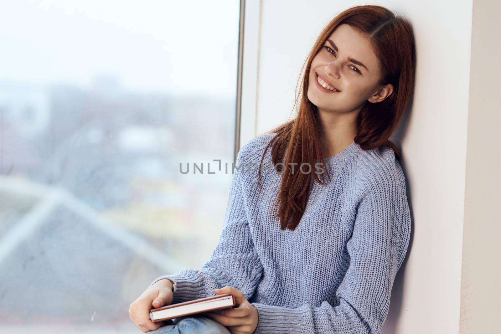 woman reading a book near the window with a cup of drink rest. High quality photo