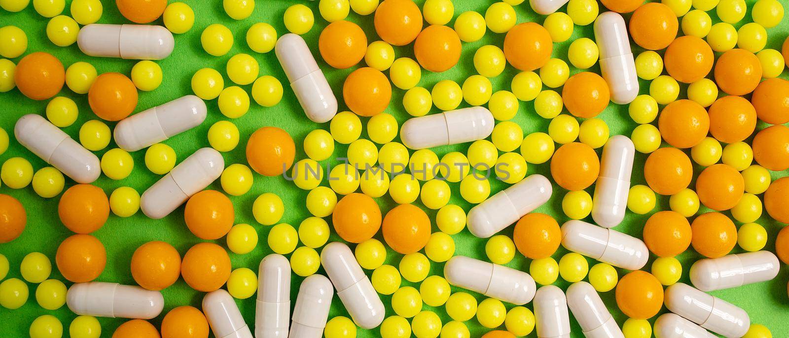 different colorful pills, capsules. Prevention, cure of influenza, coronavirus, covid-19, 2019-nCoV. yellow, orange vitamins, tablets on green background. medical healthcare, protection concept banner