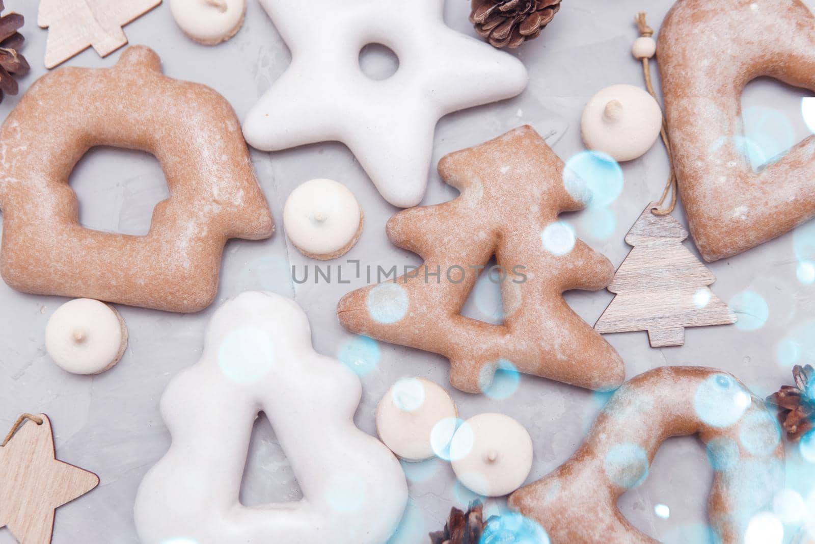Banner for Christmas and New Year gingerbread stars, houses, Christmas trees, toys on a gray concrete background, Christmas lights bokeh in the foreground.
