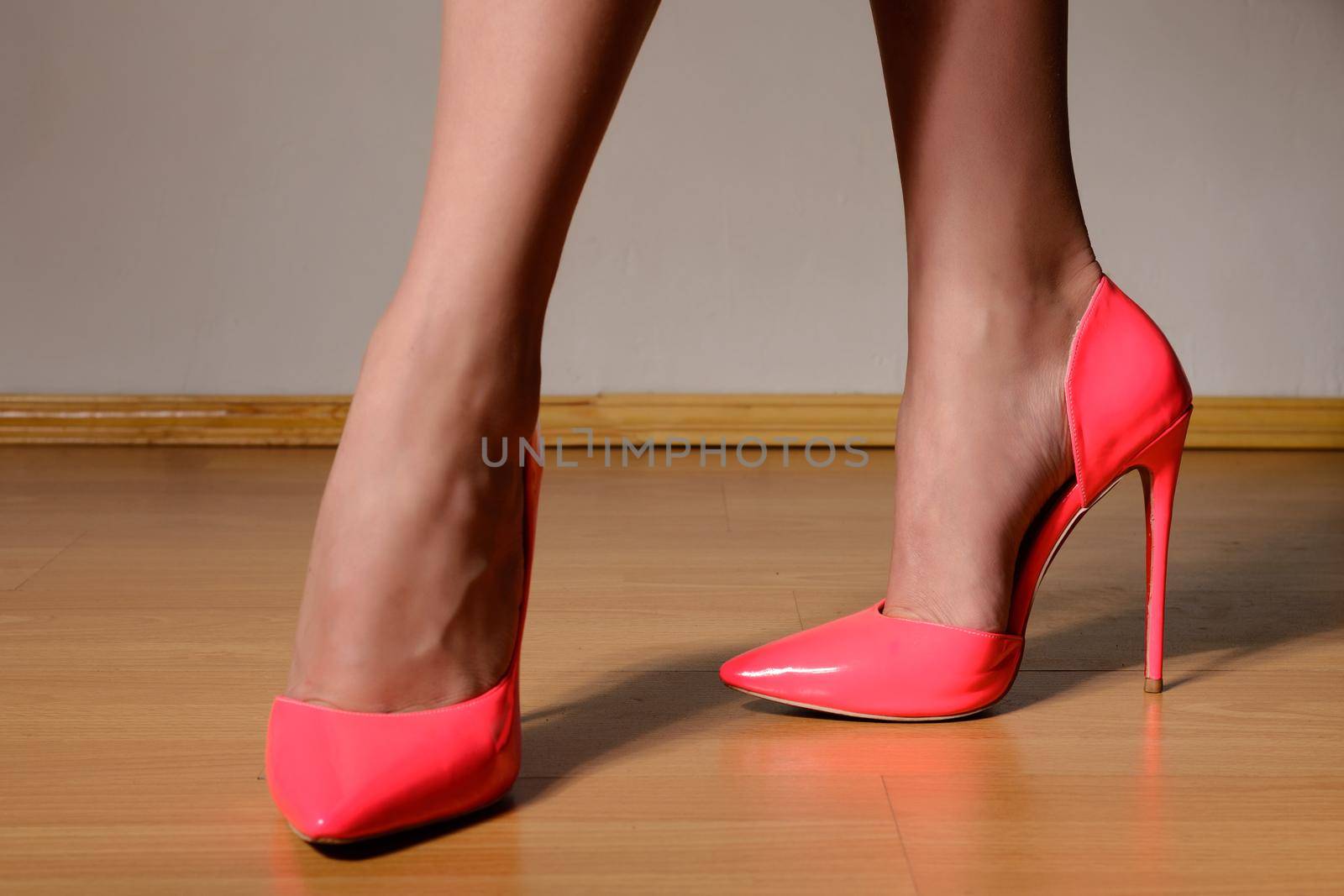 woman shapely legs wearing in fashionable pink lacquered high heel shoes. Close up view