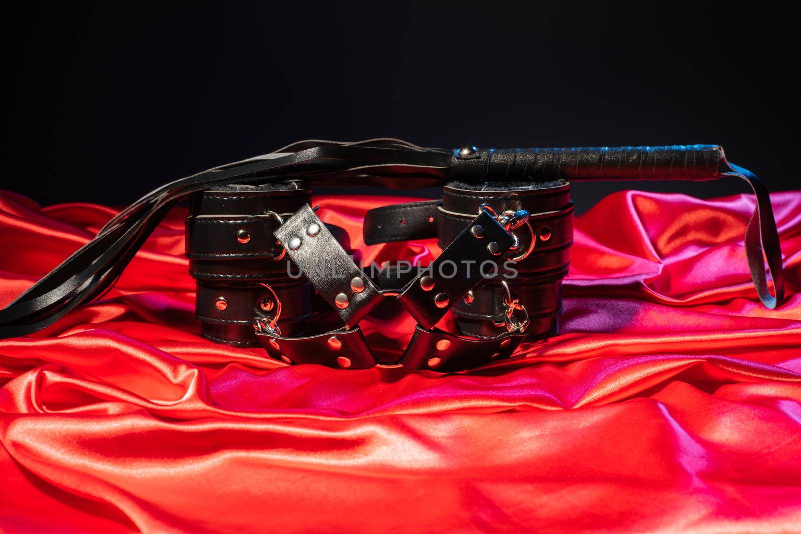Adult sex games. Kinky lifestyle. Whip and Bondage on the red linen. Bdsm outfit - Image