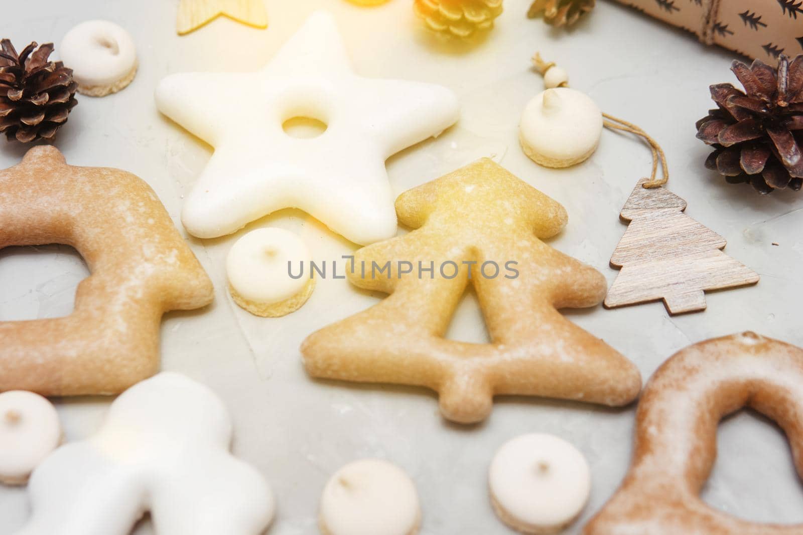 Banner for Christmas and New Year gingerbread stars, houses, Christmas trees, toys on a gray concrete background, Christmas lights bokeh in the foreground.