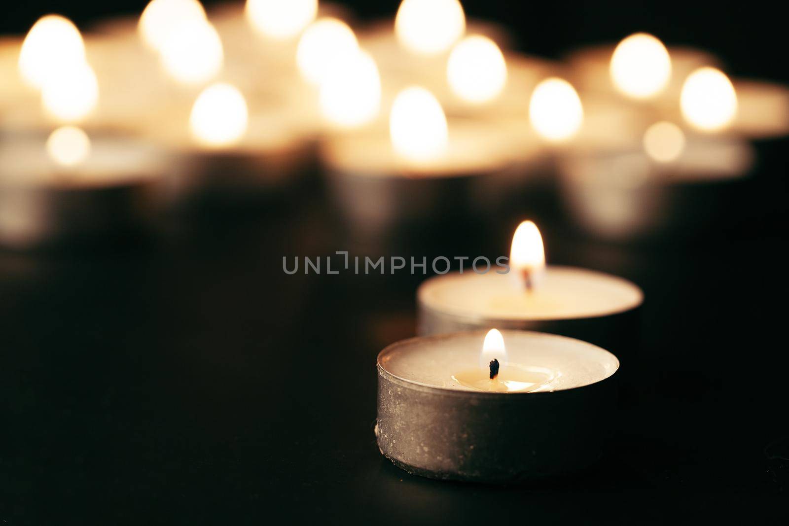 Burning candle on table in darkness, space for text. Funeral symbol