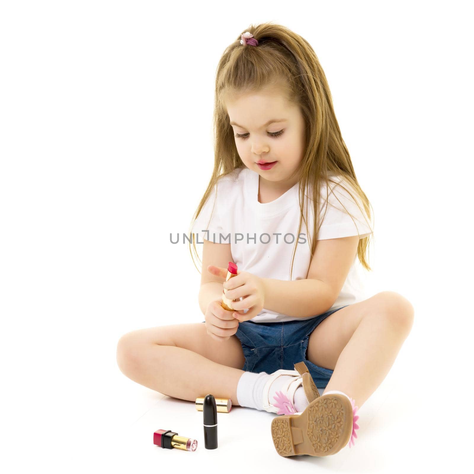Little girl paints lips with mom's lipstick. by kolesnikov_studio