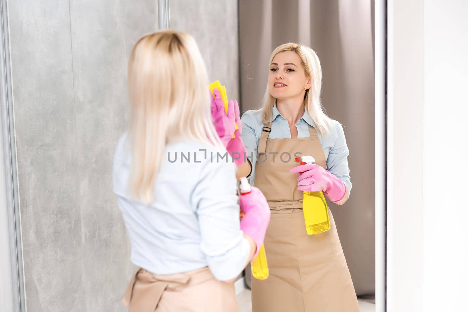Close up of woman cleaning the mirror in the bathroom
