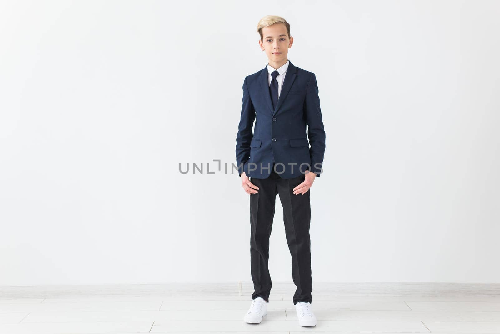 Portrait of stylish school boy teenager in white shirt and jacket against white background with copy space