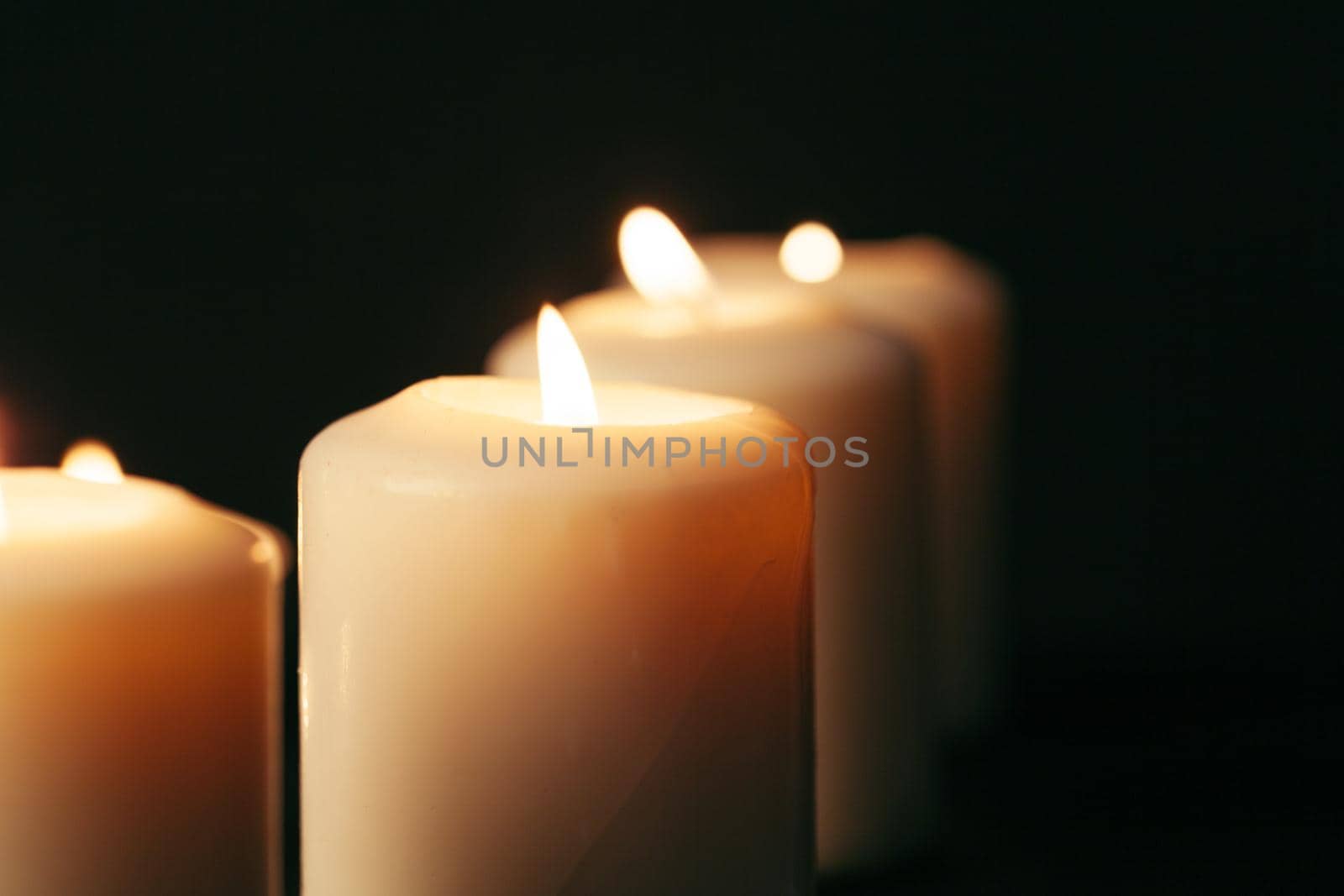 Many candles burning at night. Many candle flames glowing on dark background