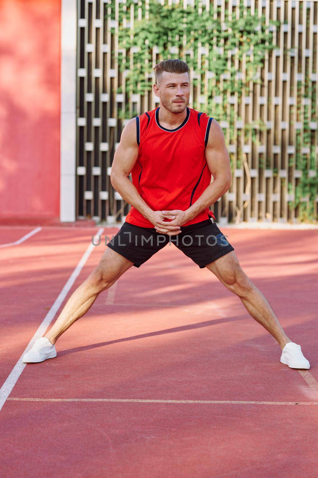 athletic man in red jersey on the sports ground exercise by Vichizh